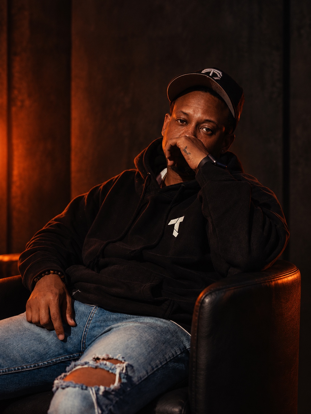 Prop the Producer seated in his studio wearing a cap and hoodie